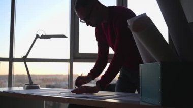 Mimar masanın üzerine planlar çizer