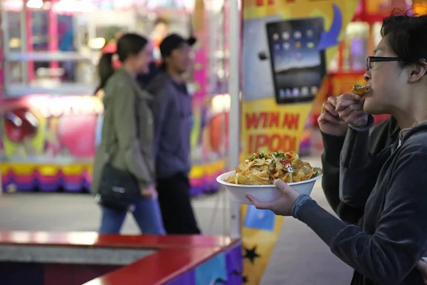 Ludzie jedzenie kręcone frytki na zachodnim wybrzeżu zabawy karnawałowe — Zdjęcie stockowe