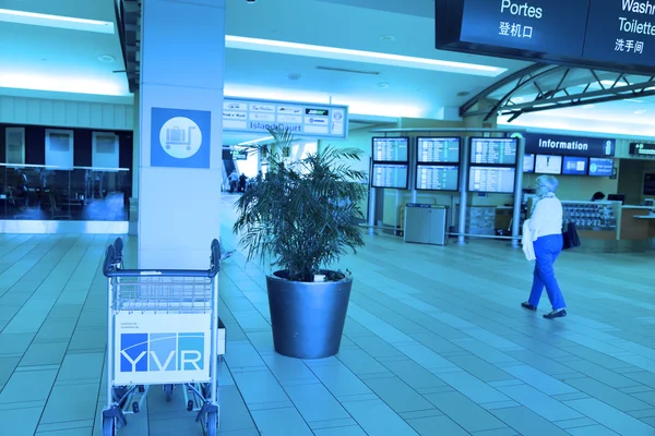 Un lato di persone che camminano all'interno dell'aeroporto YVR con toni blu . — Foto Stock