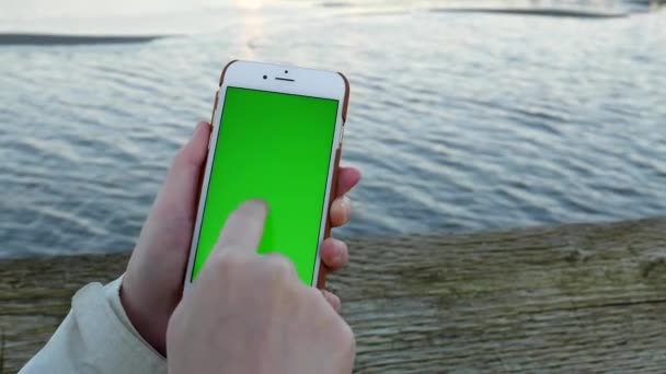 Mujer sosteniendo pantalla verde pantalla móvil teléfono inteligente con el flujo de fondo del río — Vídeos de Stock