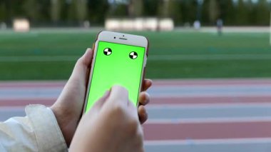 Under sporda yeşil bir ekran ile bir akıllı telefon kullanarak eller, yakın çekim