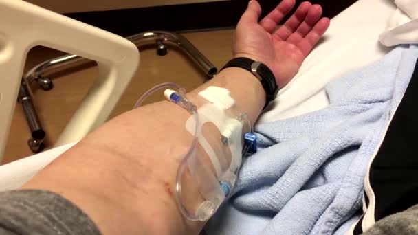 Крупним планом рука пацієнта з голкою для крапель натрію лежить на ліжку в лікарні — стокове відео