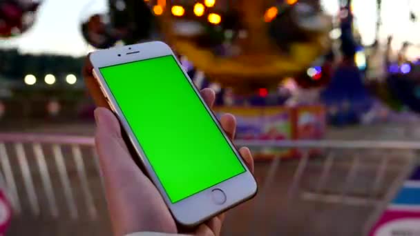 Gros plan des mains féminines tenant un téléphone intelligent avec un écran vert au carnaval des Amusements de la côte ouest — Video