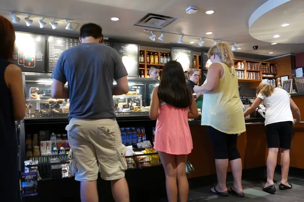 Ena sidan av personer line up för att köpa kaffe inne Starbucks butiken — Stockfoto