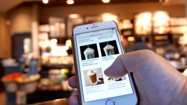 Hareket bir Starbucks içecek Starbucks mağaza içeride telefon menüsünde tarama adam