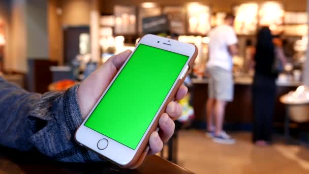 Ręka trzyma zielony ekran iphone wewnątrz sklepu Starbucks — Wideo stockowe