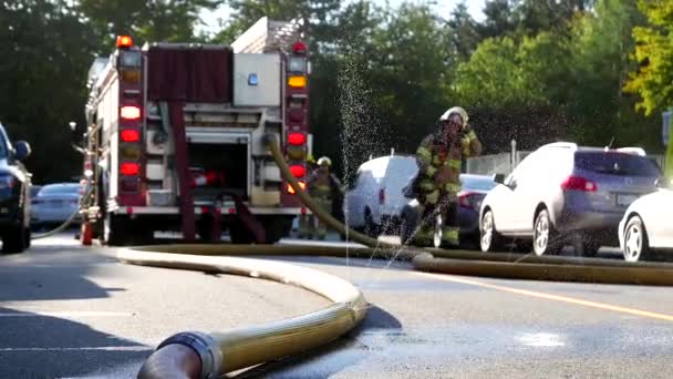 Close up hose sprays water with fire emergency personnel in rescue action. — Stock Video
