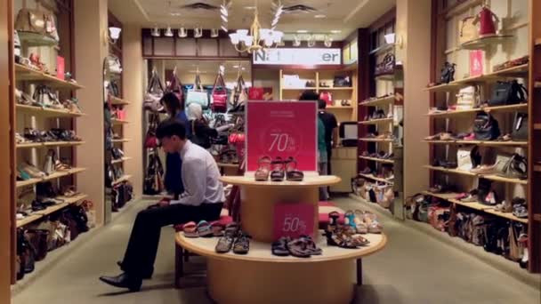 Люди смотрят на обувь в обувном магазине — стоковое видео