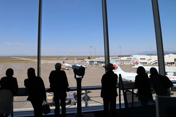 Personas dentro del aeropuerto de YVR viendo aire canada avión —  Fotos de Stock