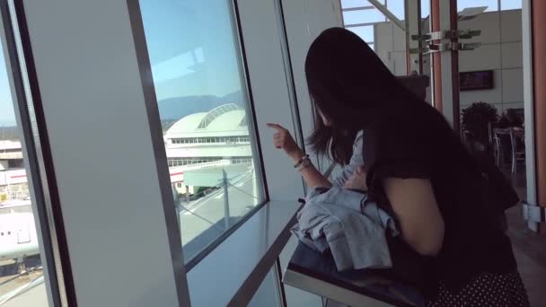 Close up of two friends looks through window at planes at airport — Stock Video