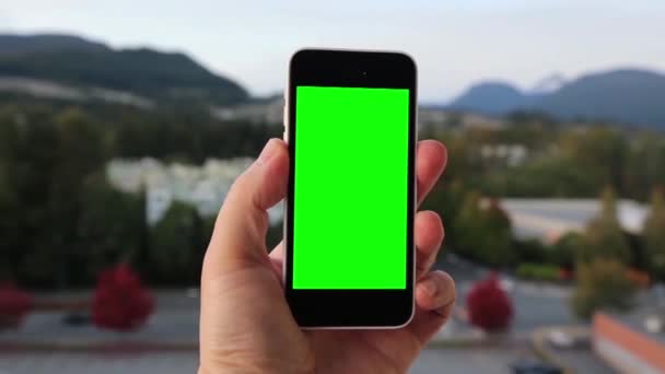 Man houdt een lege slimme telefoon met een groen scherm voor uw eigen aangepaste inhoud. — Stockvideo