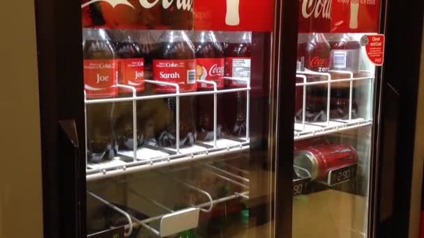 Mujer tomando coca de un refrigerador en una tienda de conveniencia . — Vídeo de stock