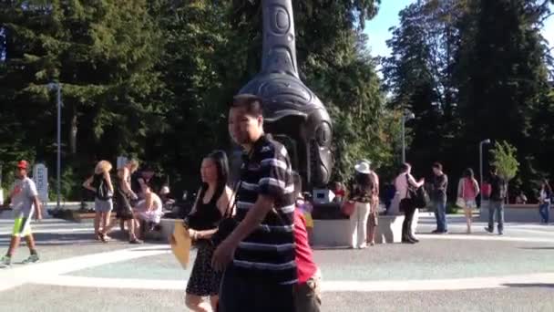 People playing fountain water beside Vancouver aquarium totem. — Stock Video