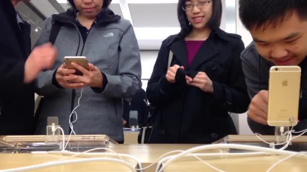 Люди, играющие в новые iPhone в магазине Apple — стоковое видео