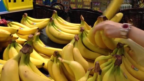 Женщина выбирает банан в продуктовом магазине — стоковое видео