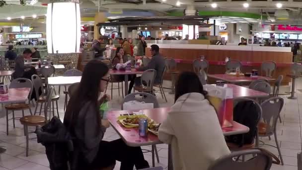 Gente disfrutando de la comida en la cafetería moderna del patio de comidas . — Vídeos de Stock