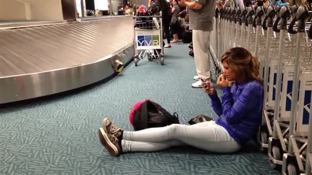Frauen lesen Handynachricht mit Gepäck, das sich um Förderband dreht. — Stockvideo