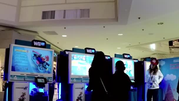 Wii staff demonstrates with people playing car racing game — Stock Video