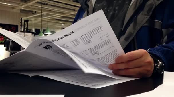 Man läser möbler katalog inuti Ikea-varuhus — Stockvideo