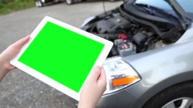 Bir kadın araba arka plan ile luma mat ile özel içerik için yeşil bir ekran ile boş bir tablet Pc tutar