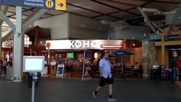 Personas con equipaje frente al restaurante y bar Koho dentro del aeropuerto YVR en Vancouver BC Canadá . — Vídeos de Stock