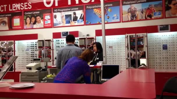 Gafas de compra de clientes dentro de tienda óptica — Vídeo de stock