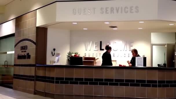 Zwei schöne Empfangsdame hinter dem Servicetisch am Gästeservice-Schalter in einem lauten Einkaufszentrum. — Stockvideo