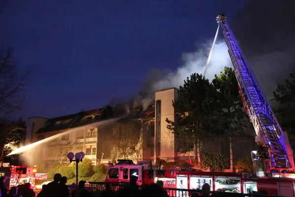 Tripulación de bomberos luchando contra incendio complejo de apartamentos por la noche — Foto de Stock