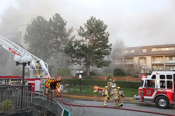 Tripulación de bomberos luchando contra incendio complejo de apartamentos Imágenes de stock libres de derechos