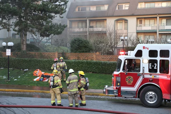 Tripulación de bomberos luchando contra incendio complejo de apartamentos Imagen de stock