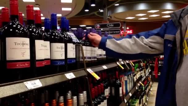 A hand takes bottles of wine from the shelf. — Stock Video