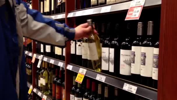 A hand takes bottles of wine from the shelf. — Stock Video