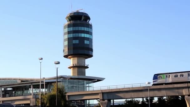 Skytrain προαστιακό σιδηροδρομικό σύστημα στο Yvr αεροδρόμιο σταθμό με φόντο Πύργος ραντάρ ελέγχου του αεροδρομίου — Αρχείο Βίντεο