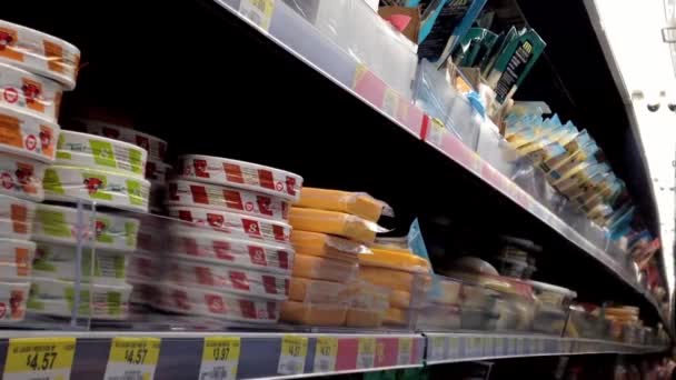 Man selecting cheese and reading label in grocery store at dairy and forzen department. — Stock Video