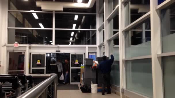 People walking through the doors of superstore entrance with cleaning window man — Stock Video