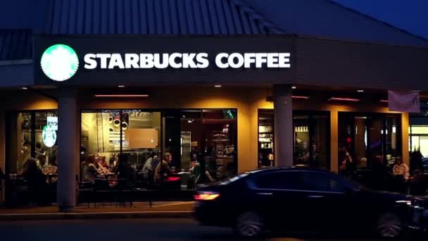 Lidé se těší kávu uvnitř kávu Starbucks v noci — Stock video
