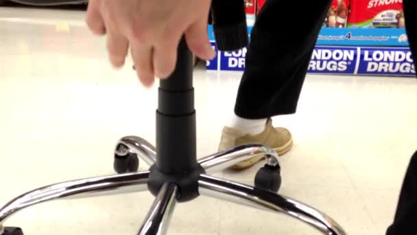 Man trying new office chair inside London Drugs store — Stock Video