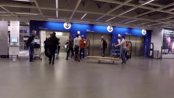 People pushing their furniture on shopping cart to elevator inside Ikea store — Stock Video