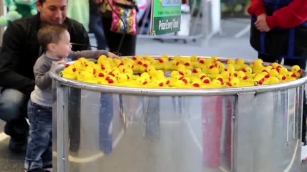 Primer plano niño la captura de patos amarillos flotan en el juego de agua en el Carnaval de atracciones de la costa oeste — Vídeo de stock