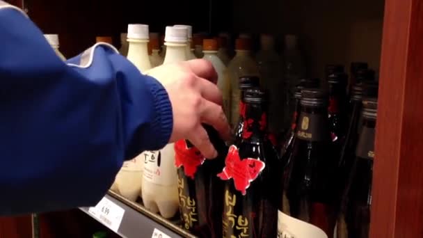 Ένα χέρι παίρνει μπουκάλια κρασί Κορέα από το ράφι. Ψώνια και επιλέγοντας ένα μπουκάλι — Αρχείο Βίντεο