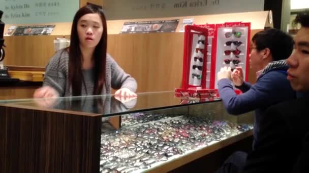 Female optician guides and assists male to choose a new pair of glasses — Stock Video