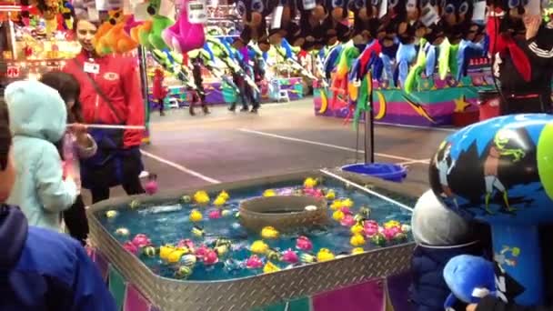 Atrapar peces de colores flotan en el juego de agua en el carnaval de atracciones de la costa oeste — Vídeo de stock