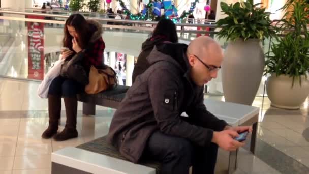 People reading mobile phone message at rest area inside shopping mall — Stock Video
