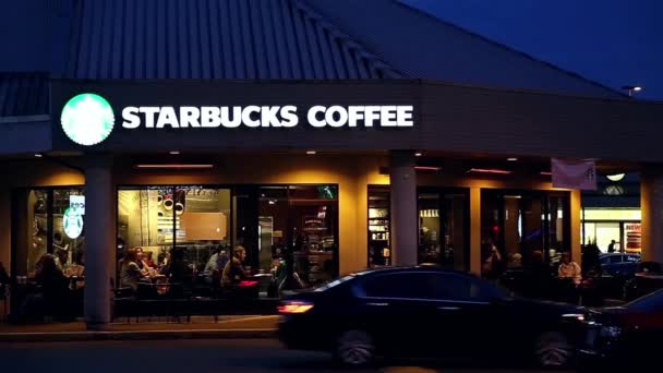 Mensen genieten van koffie binnen Starbucks koffie bij nacht — Stockvideo