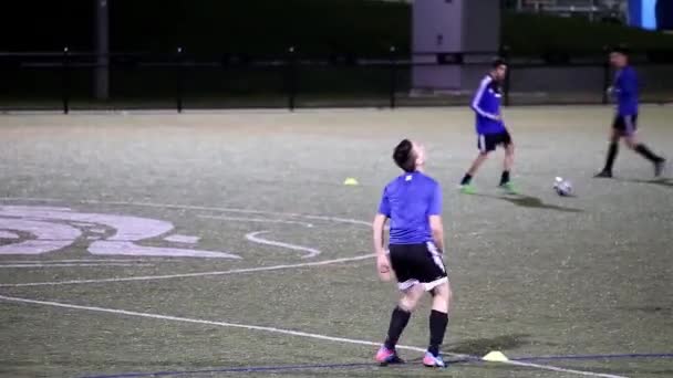 Ночная съемка юношей, играющих в футбол на спортивном поле — стоковое видео
