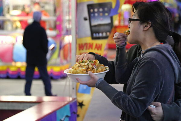 People eating curly fries at the West Coast Amusements Carnival