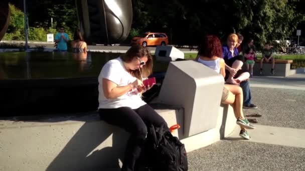 Mujer leyendo mensaje al lado del agua de la fuente fuera del acuario de Vancouver . — Vídeos de Stock