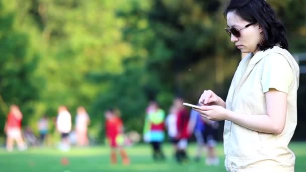 Mujer leyendo mensaje de teléfono móvil en el campo del deporte — Vídeos de Stock