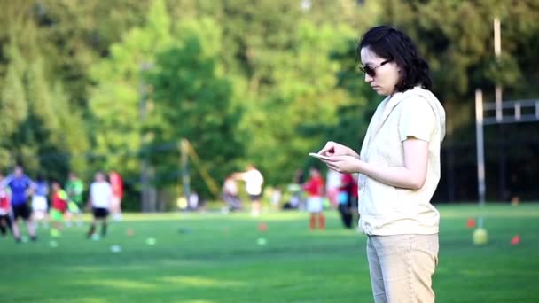 Mulher lendo mensagem de telefone celular no campo do esporte — Vídeo de Stock