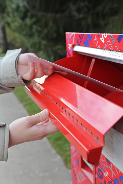 Hand sending a tax report letter in a red mail box — Stock Photo, Image